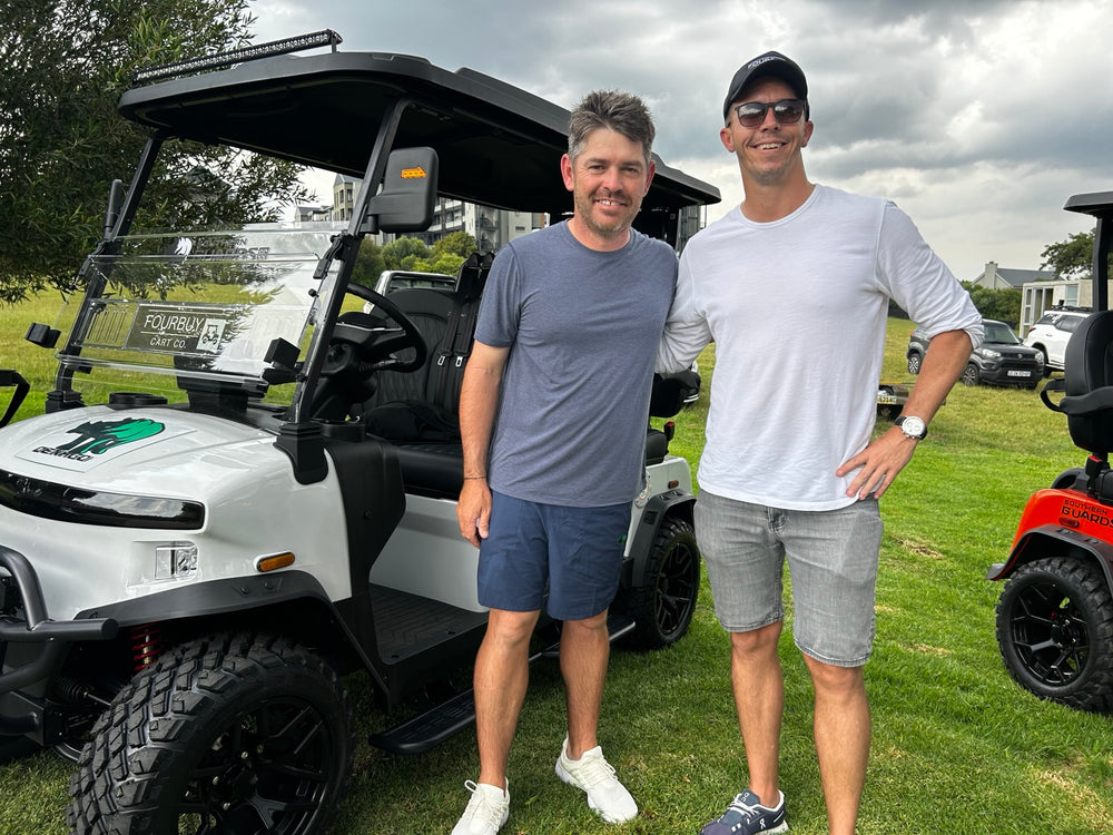 Two people standing beside a Fourbuy-branded golf cart
