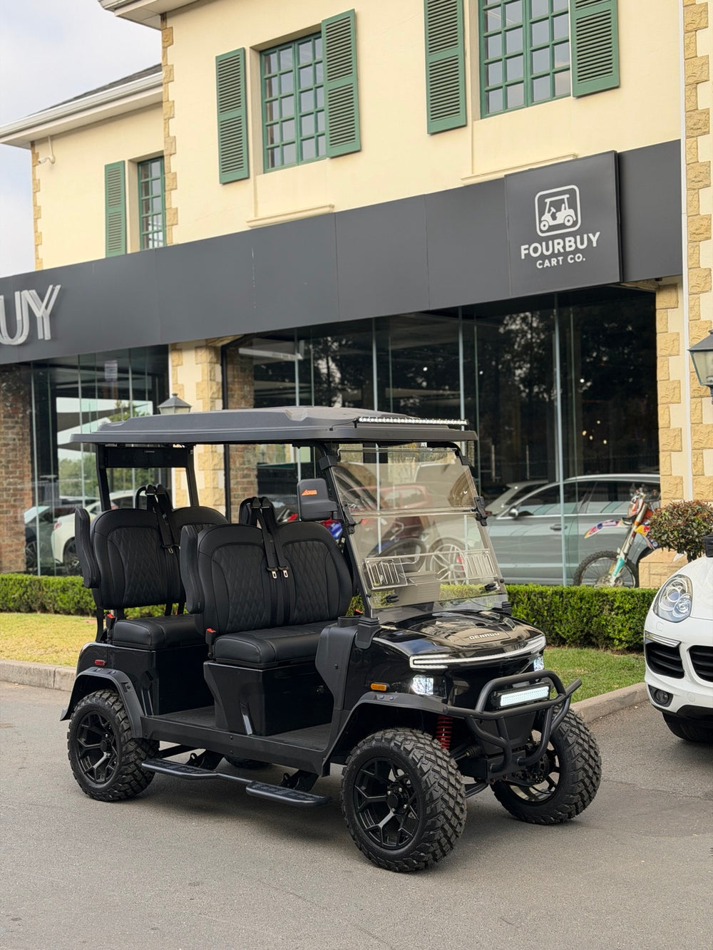 Black golf cart outside the Fourbuy Cart Co showroom entrance