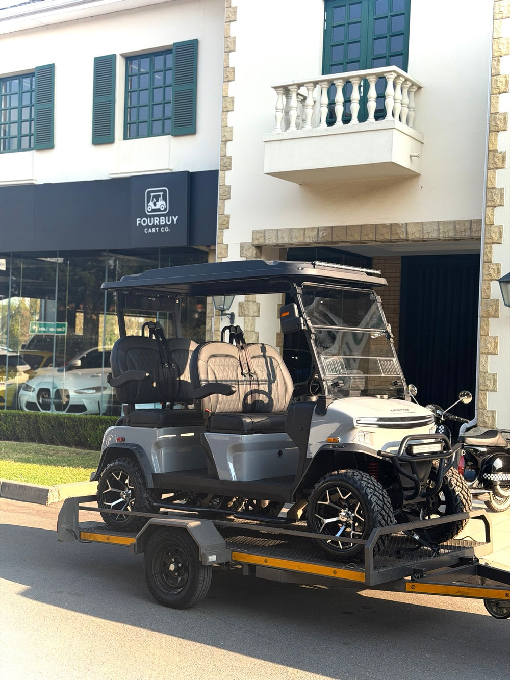 Golf cart loaded on a trailer outside the Fourbuy Cart Co showroom