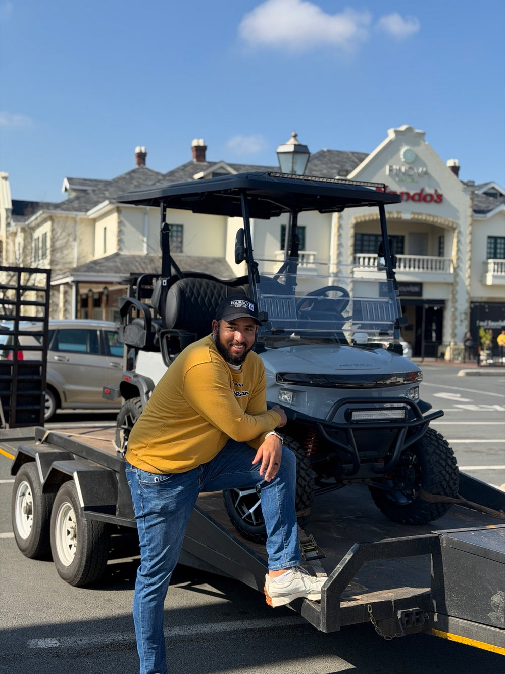 A person beside a golf cart on a trailer outside the Fourbuy showroom