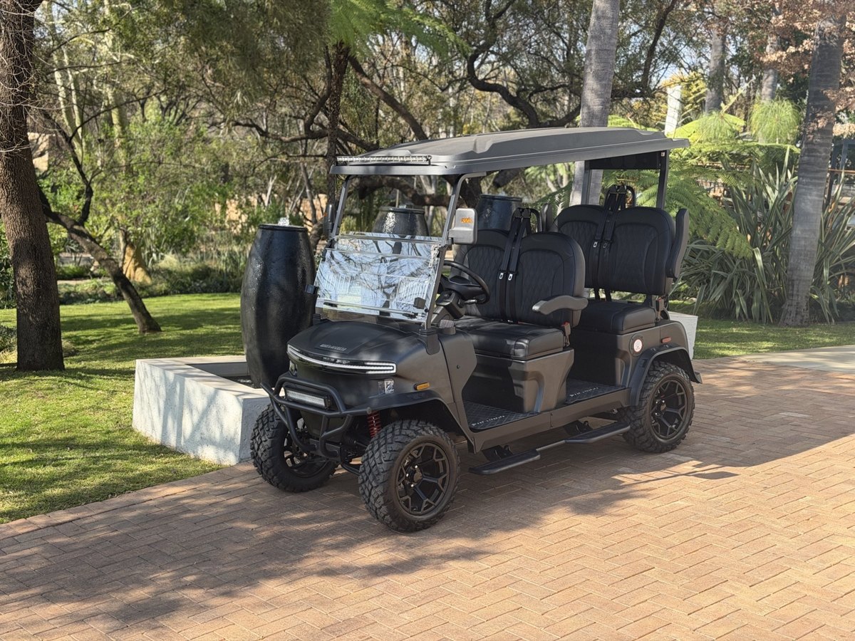 Black cart parked in a leafy garden