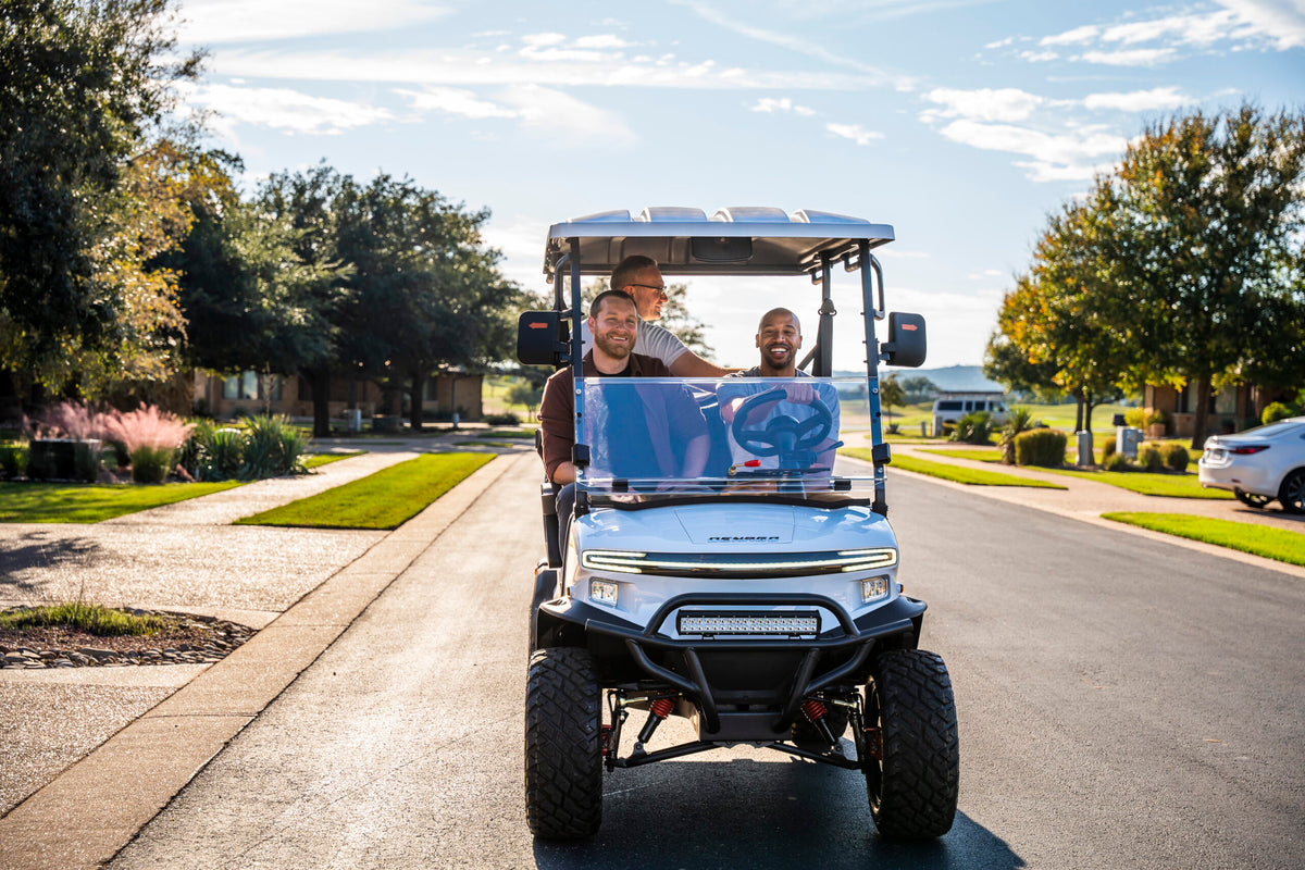 White Denago Nomad XL driving along a landscaped residential road
