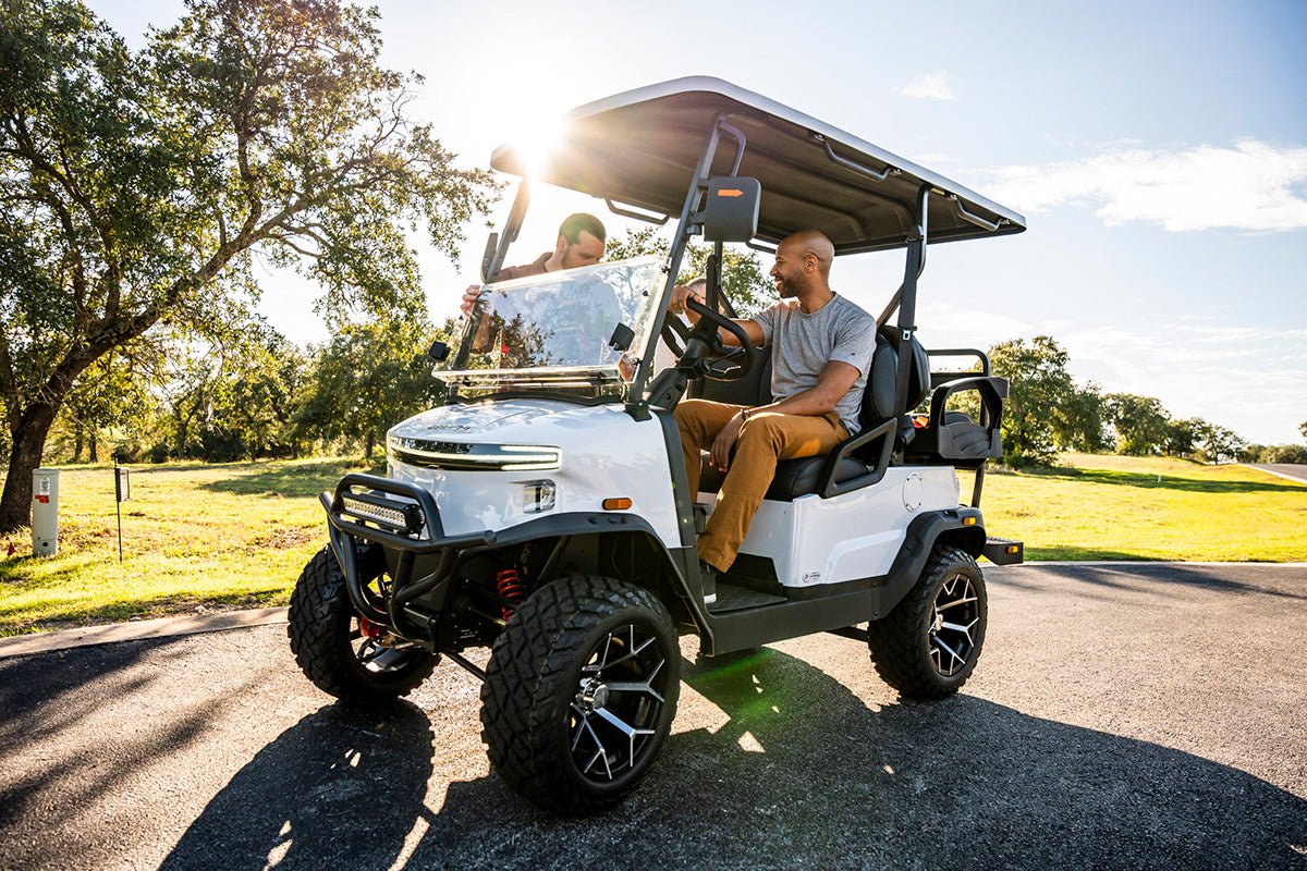 Golfers chatting beside a white Denago Nomad XL at a golf course