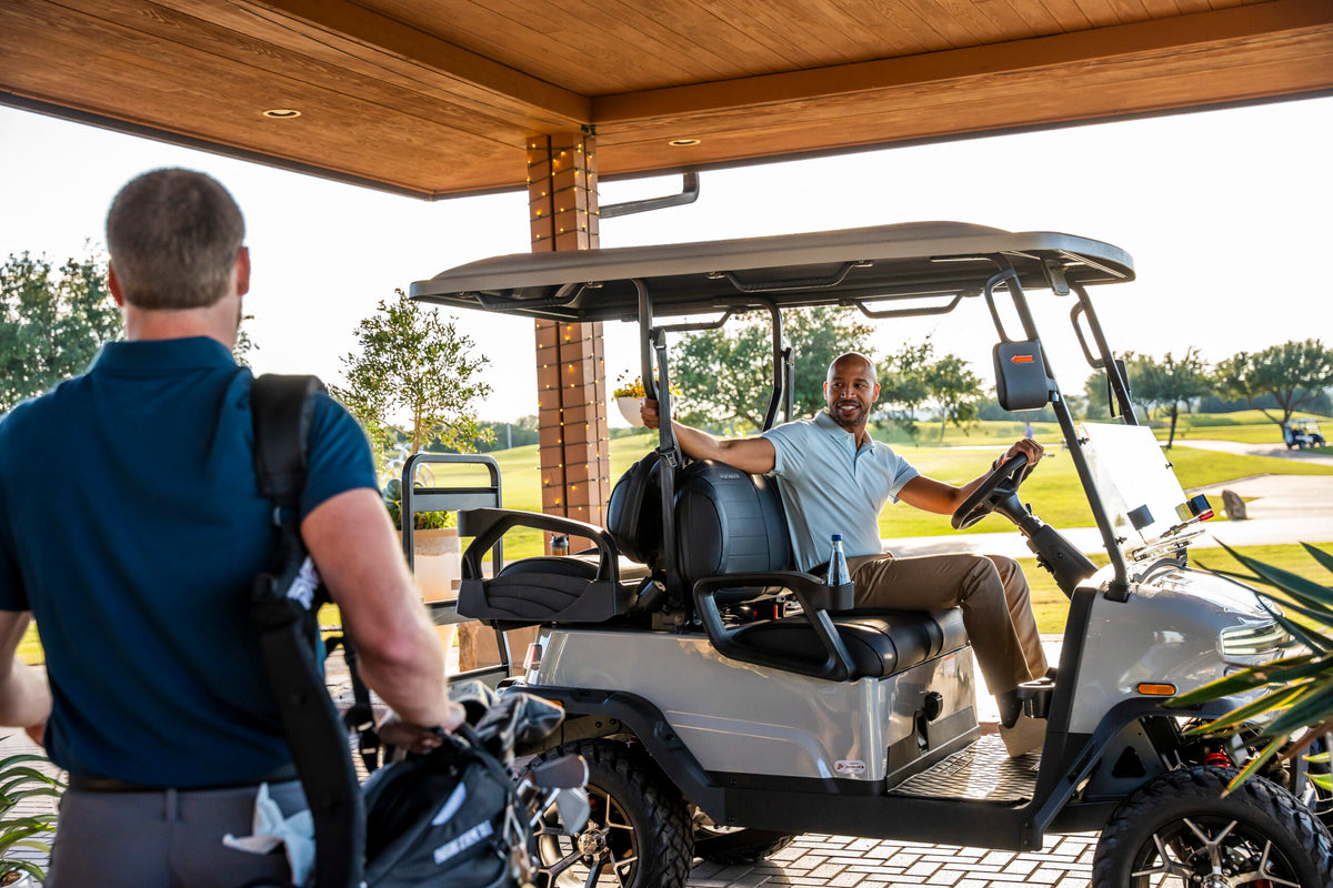 Golfer approaching a white Denago Nomad XL under a timber shelter