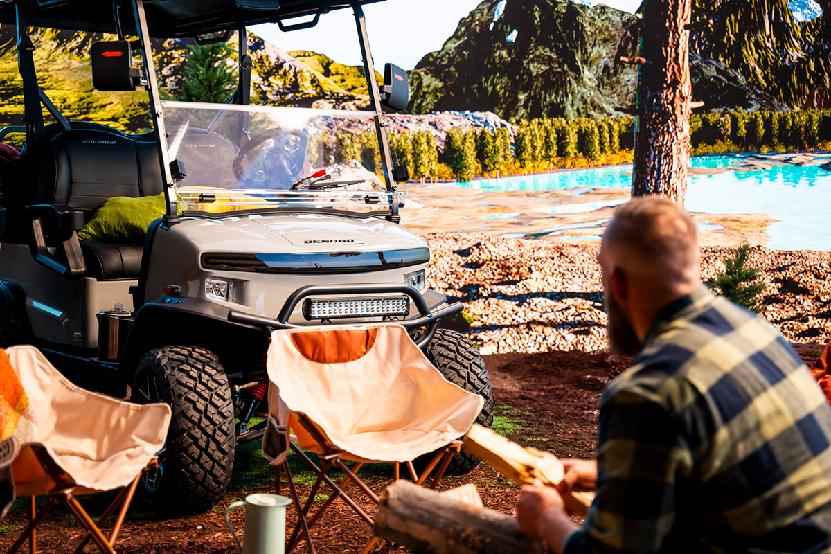 Denago Nomad XL parked beside a lakeside campsite with outdoor chairs