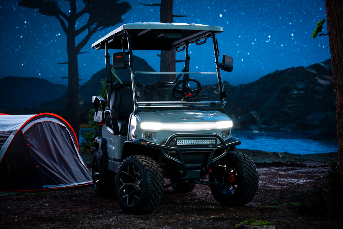 Denago Nomad XL with its lights on beside a tent and lake at night