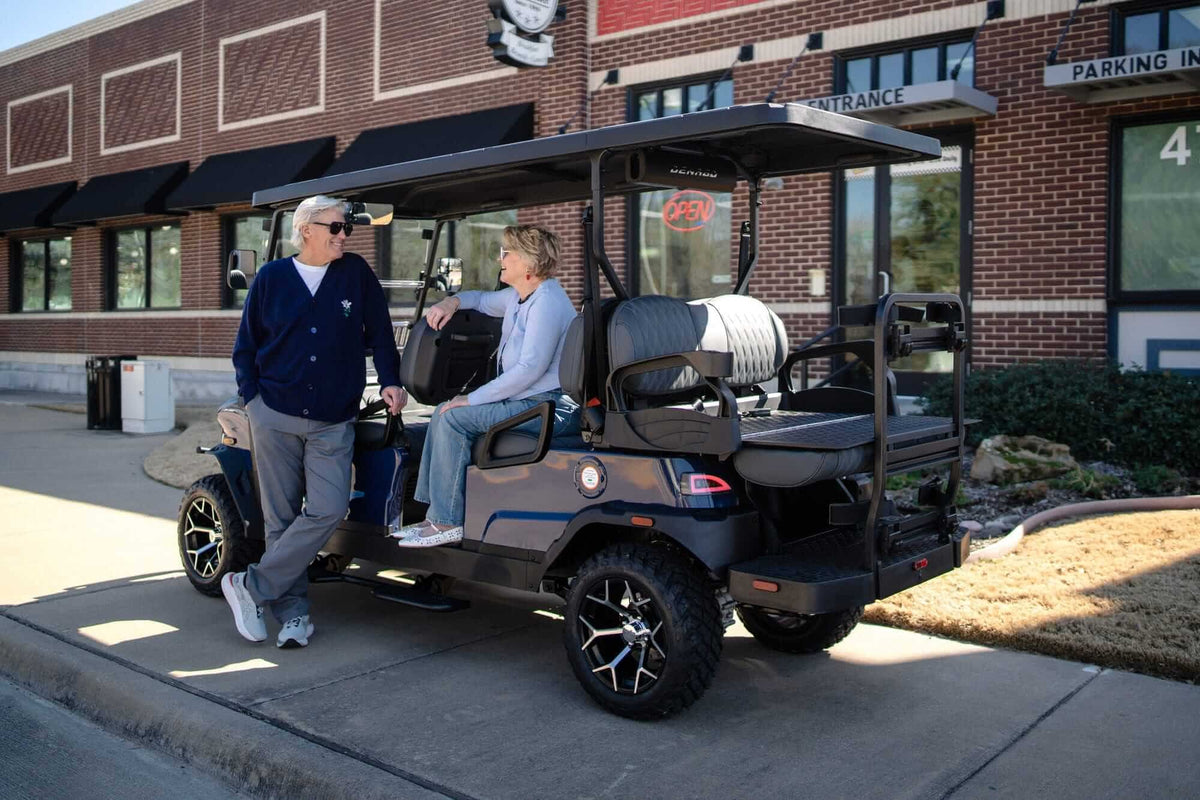 Couple beside a grey Denago Rover XL-6 parked outside a local building