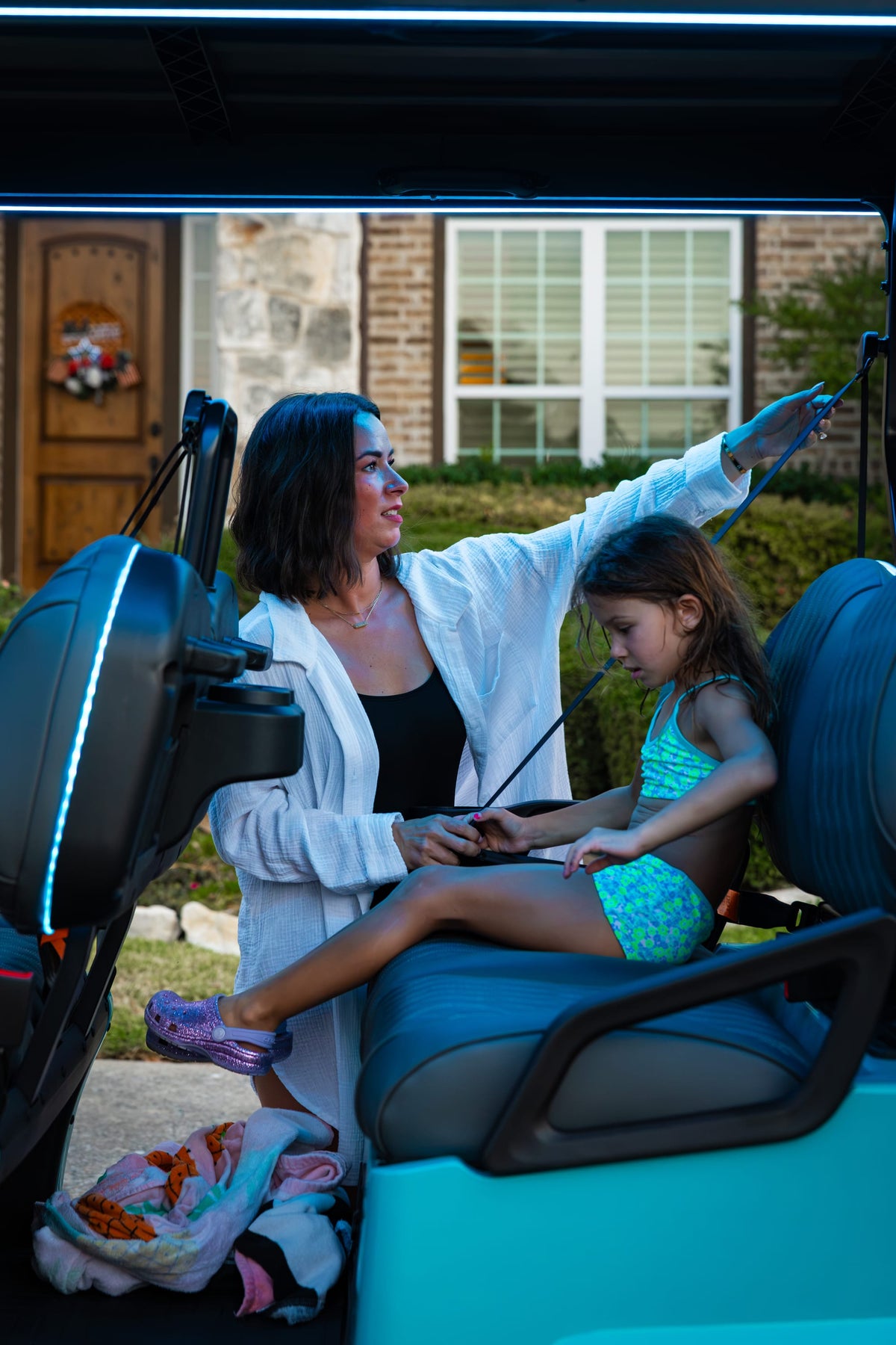Mother helping a child seated on the rear-facing bench of an aqua Denago Rover XL-6