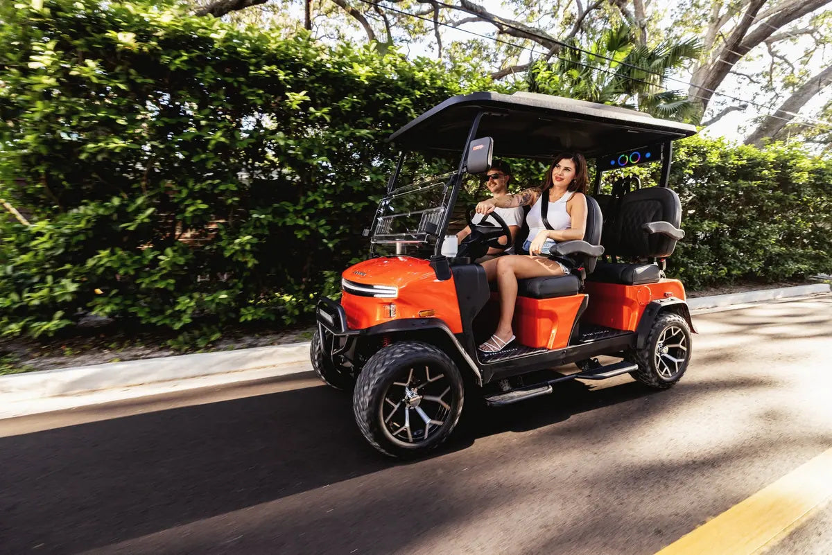 Two women enjoying a leafy neighbourhood drive in an orange Denago Rover XL
