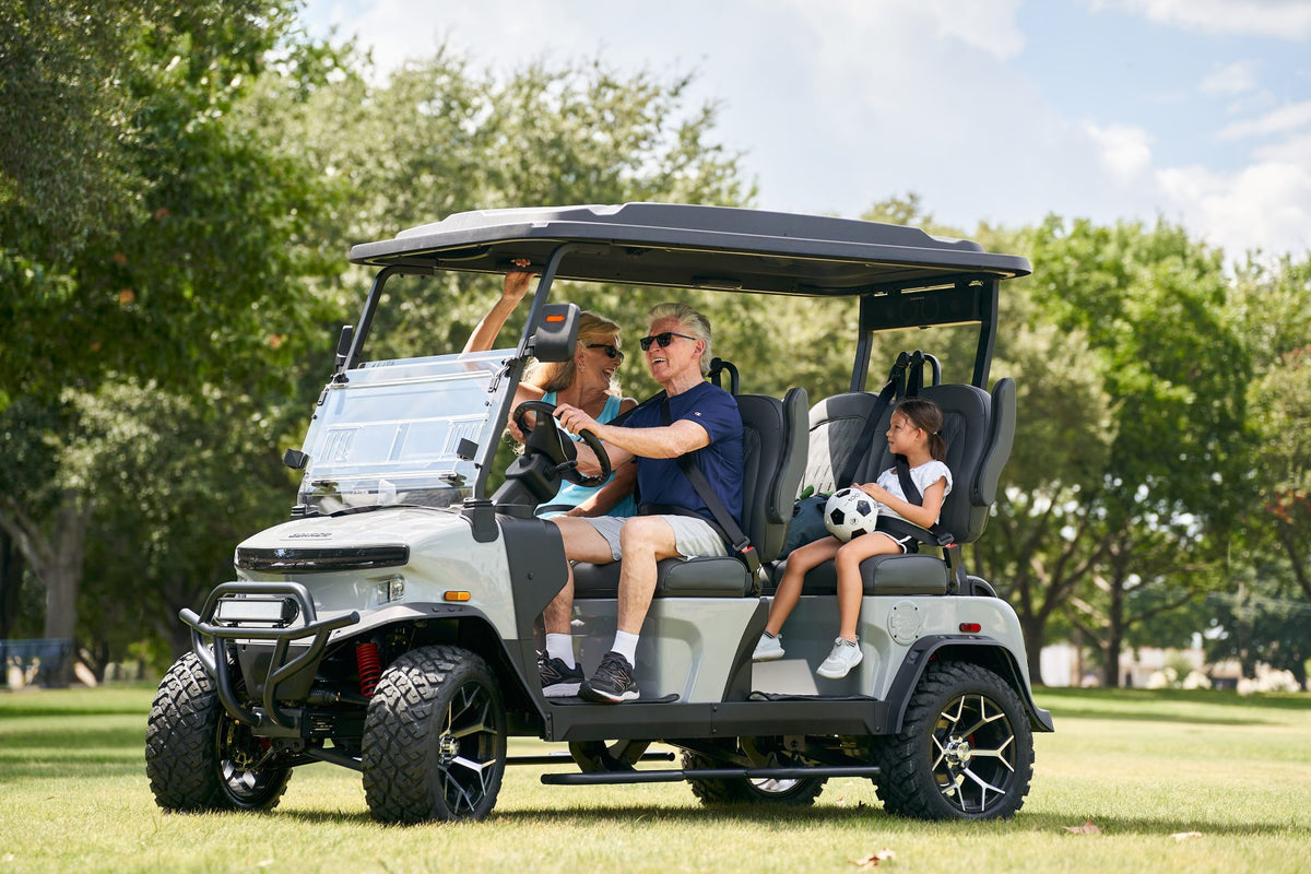 Family in a white Denago Rover XL on the grass with a child holding a football