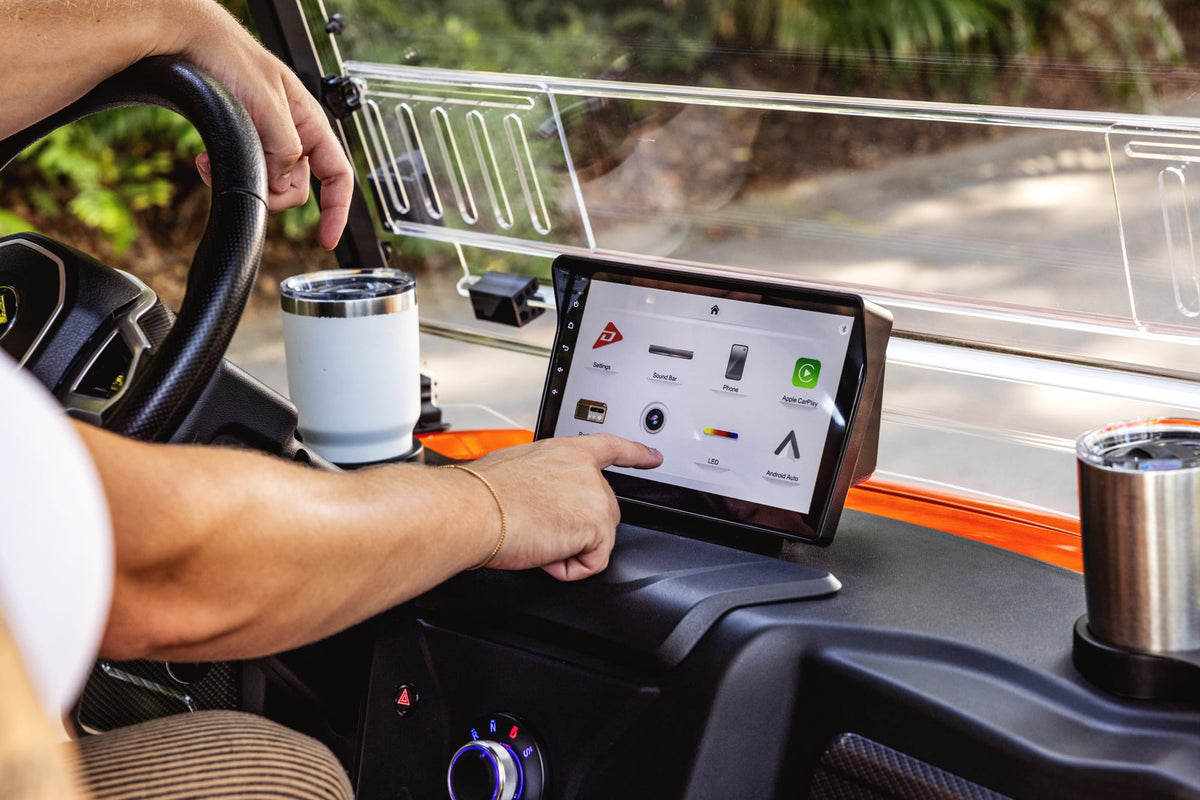 Passenger using the touchscreen in the dashboard of an orange Denago Rover XL