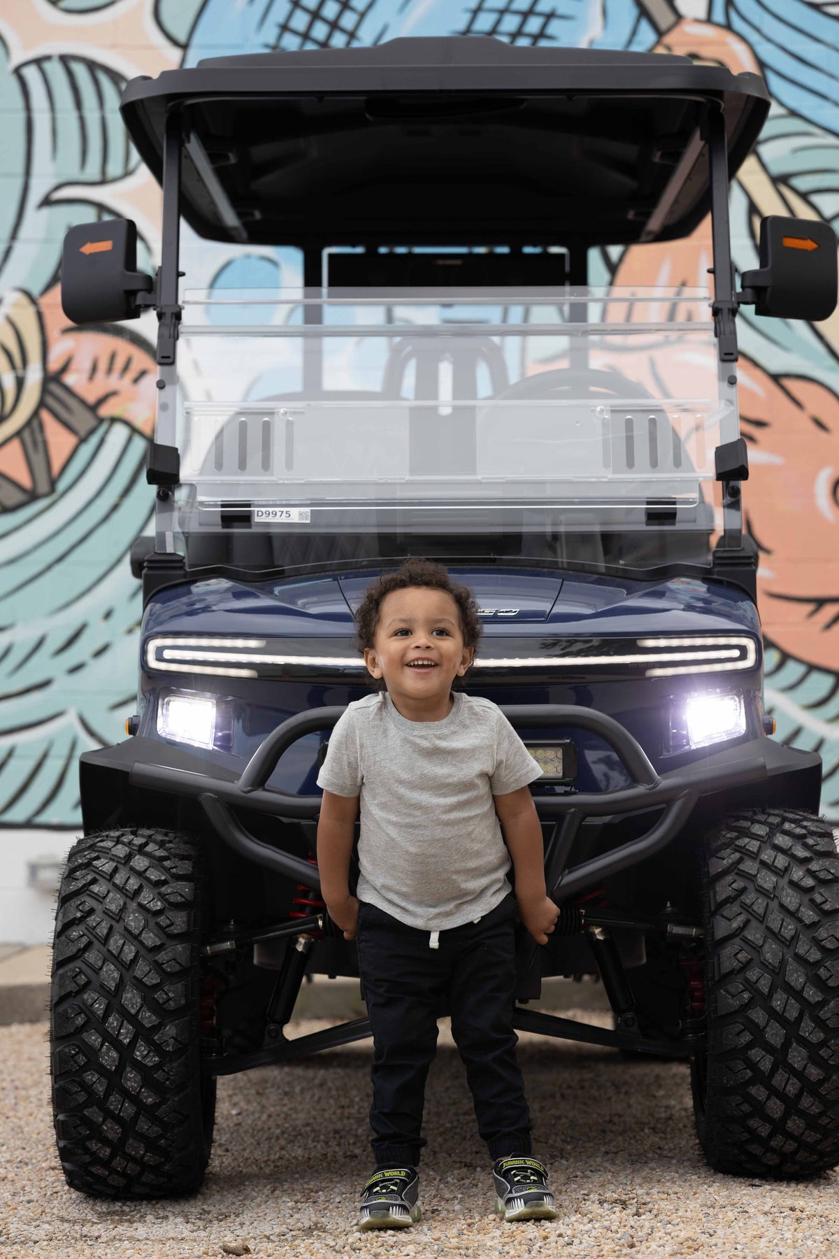 Child standing in front of a Denago Rover XL beside a colourful mural