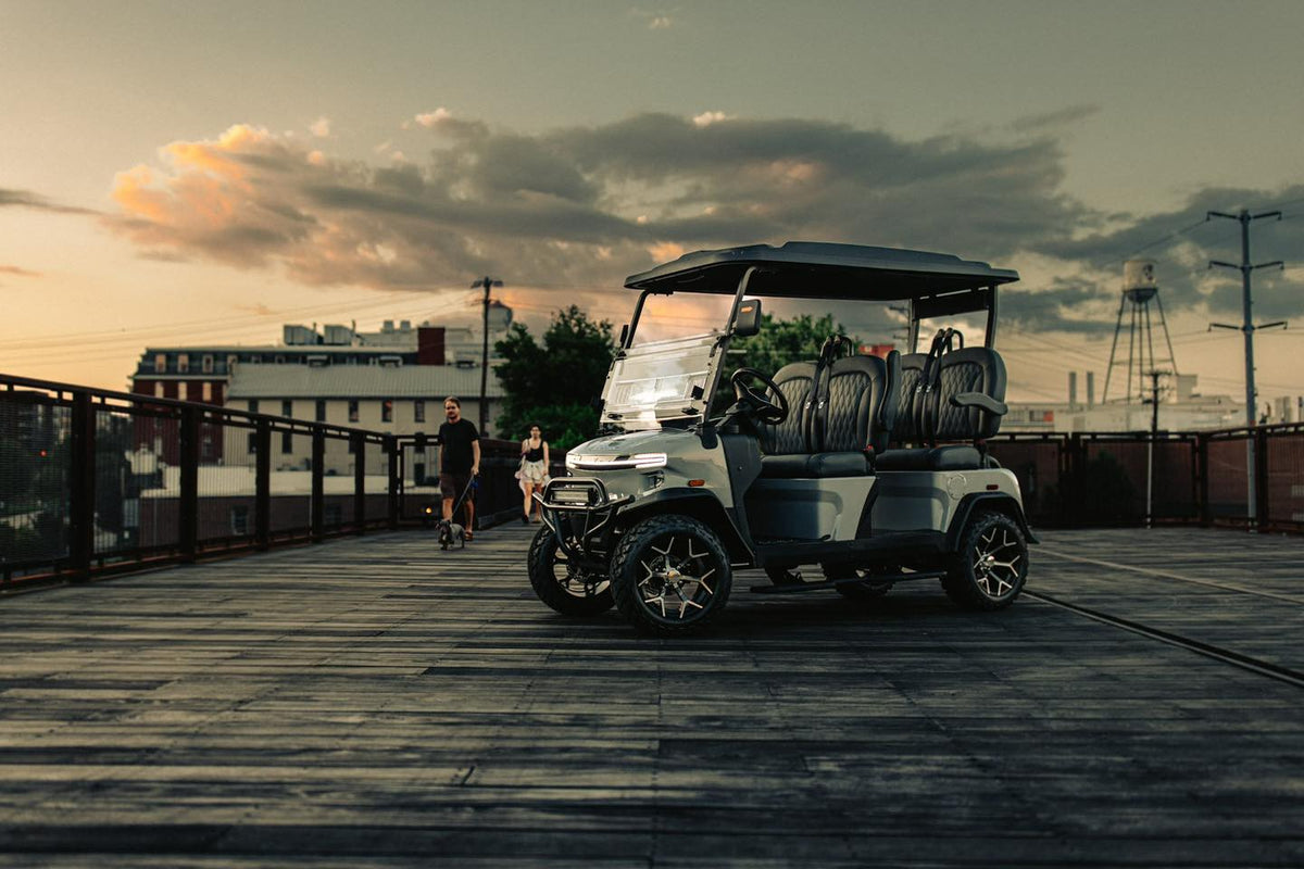 Silver Denago Rover XL showing its four forward-facing seats on a wooden boardwalk at sunset
