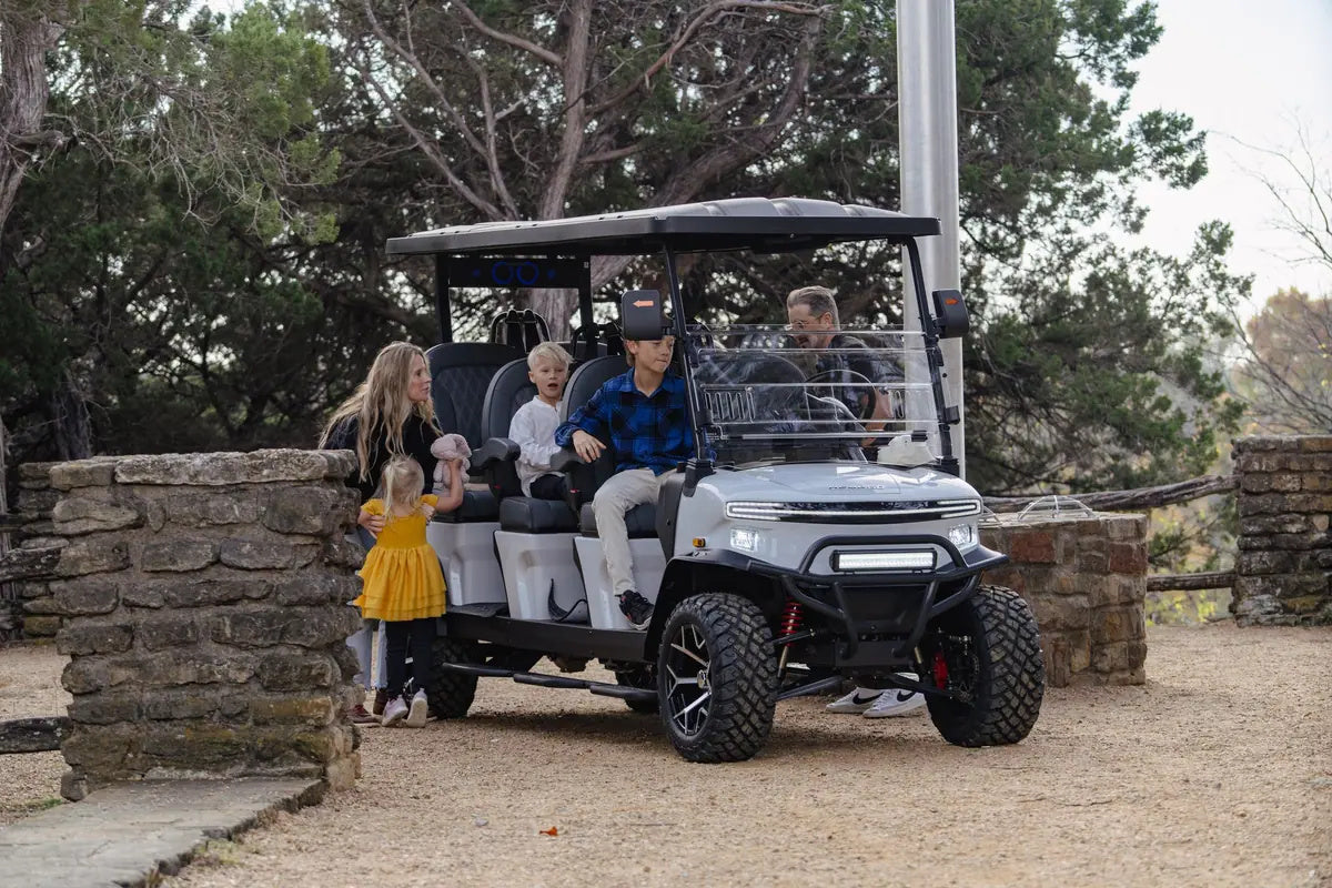 Family gathered around a white Denago Rover XXL beside a stone wall and trees