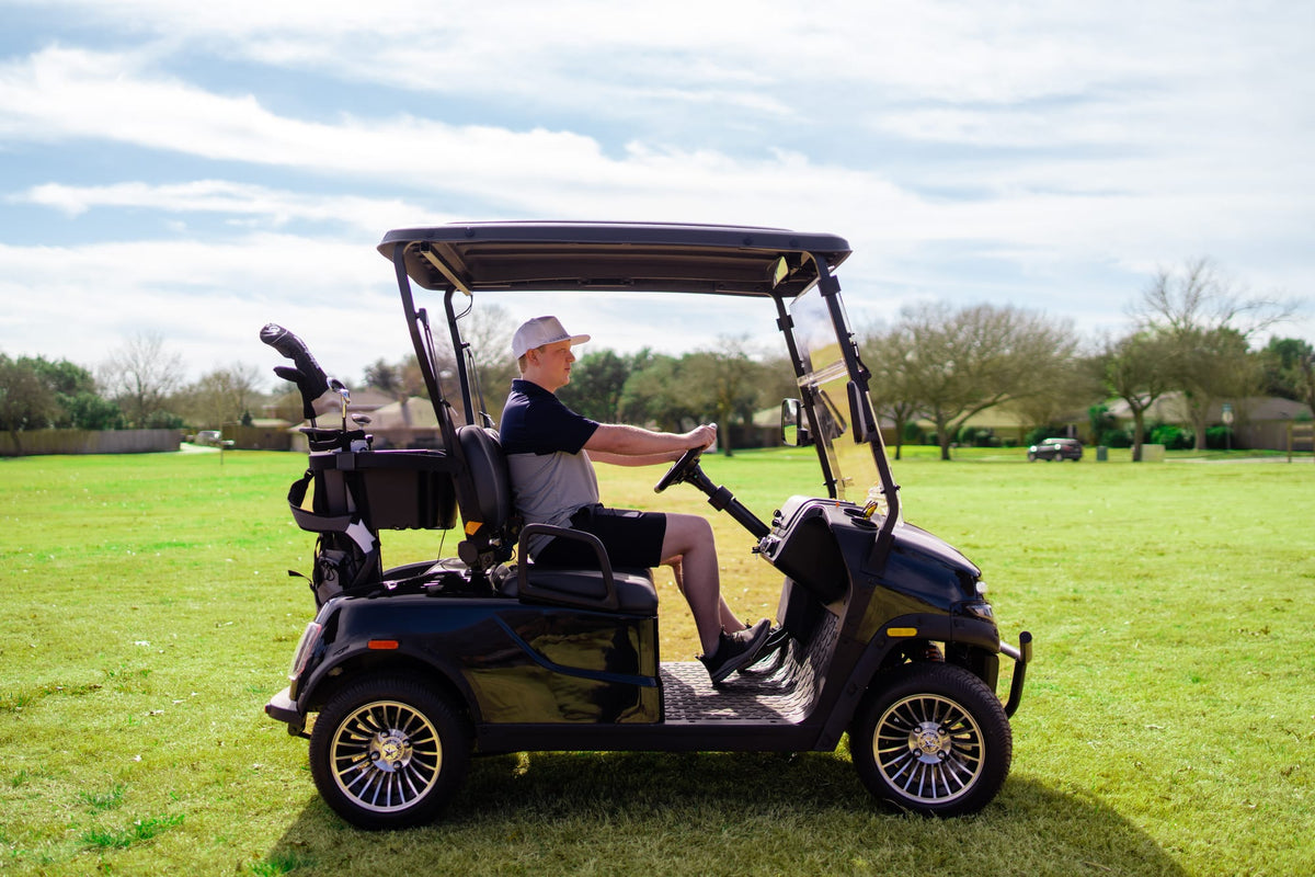 Golfer driving a black Denago Scout 2 across the fairway with golf bags behind the seat