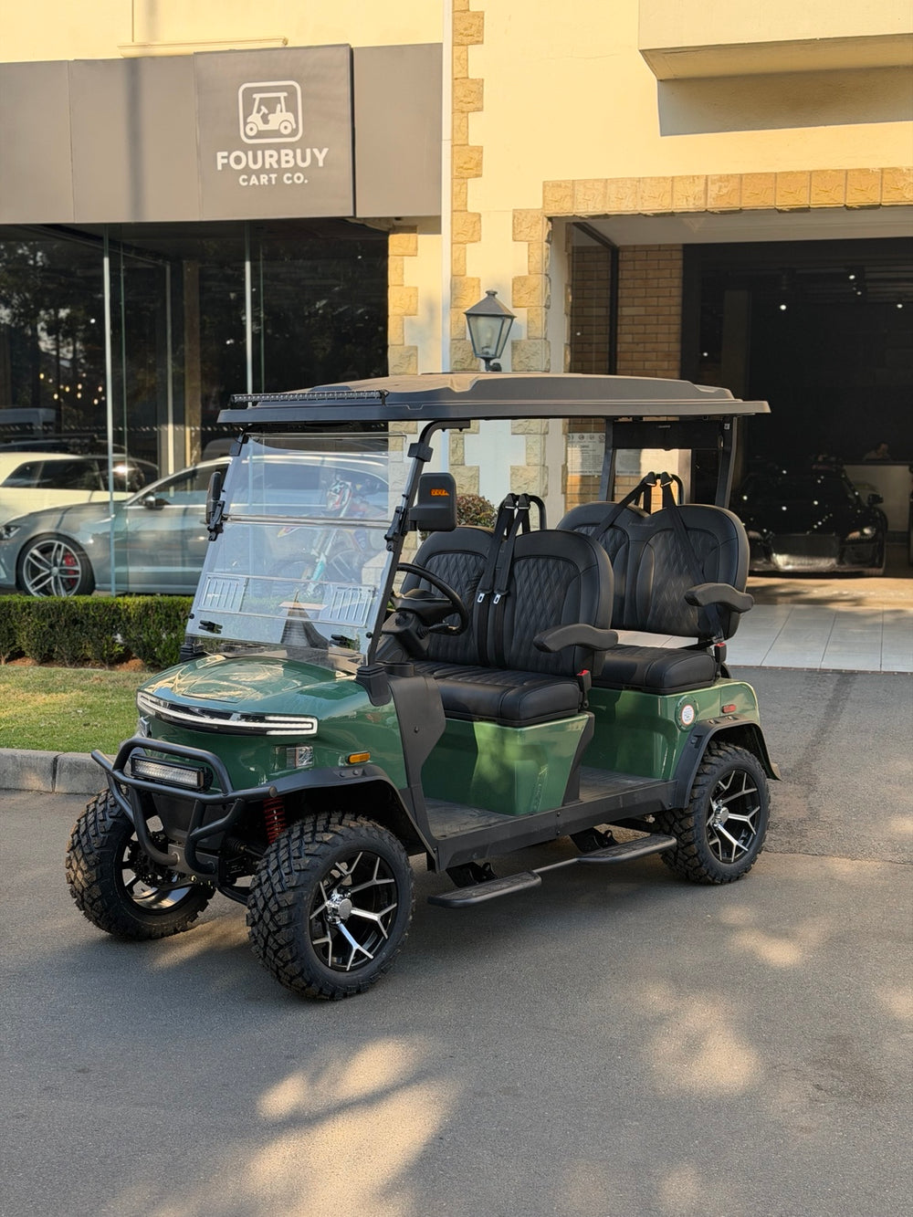 Green golf cart parked in front of the Fourbuy Cart Co showroom